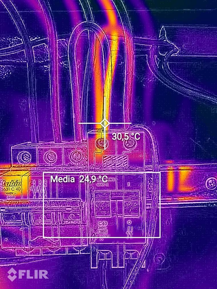 Imagen térmica FLIR de un tablero: el borne de entrada de una térmica marca 30,5 °C frente a una media de 24,9 °C en la zona de referencia